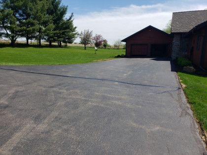 A driveway leading to a house with trees in the background.