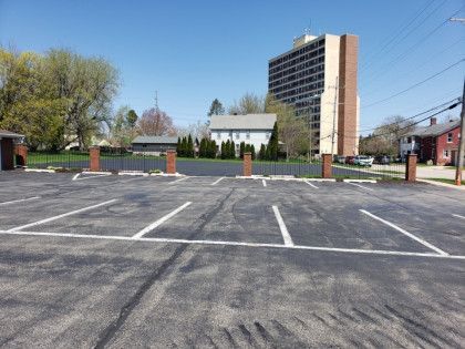 An empty parking lot with a tall building in the background.