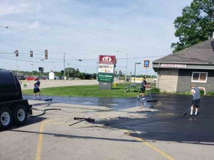 A group of people are cleaning a parking lot in front of a building.