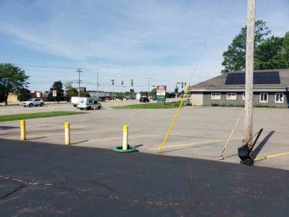 A parking lot with a pole in the middle of it and a building in the background.