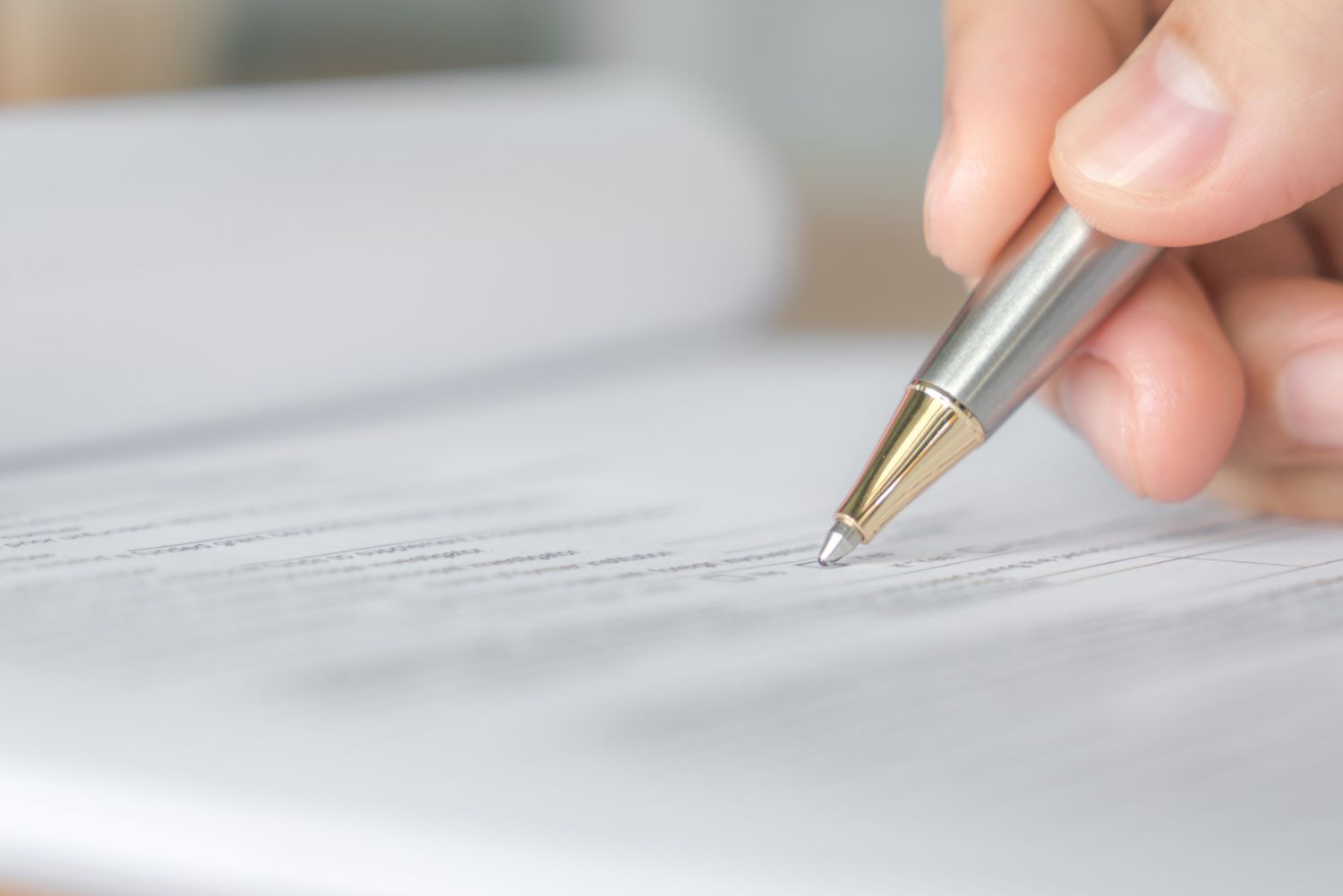 Hand writing with a silver pen on a white document close-up