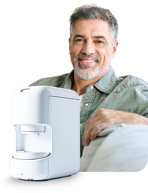 Man smiling, sitting next to a white medical device.
