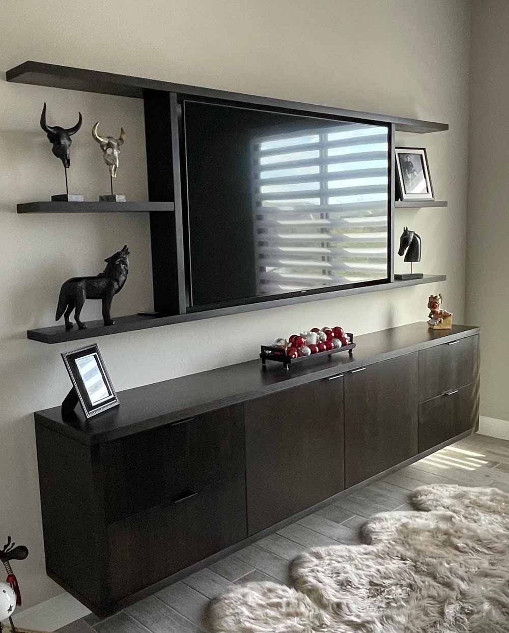 A dark wood floating media console and matching wall shelves display decor, including statues, around a wall-mounted TV.