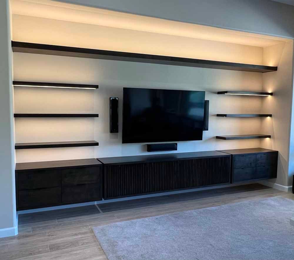 Wall-mounted dark wood media console and shelving unit with integrated LED lighting and a flat-screen TV in a modern room.