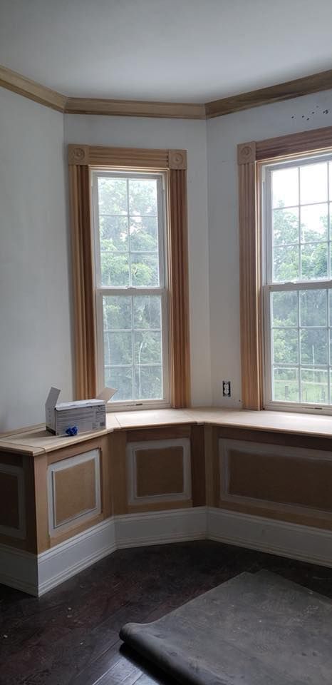 Empty bay window nook with white trim, wood accents, and dark floor in a bright room