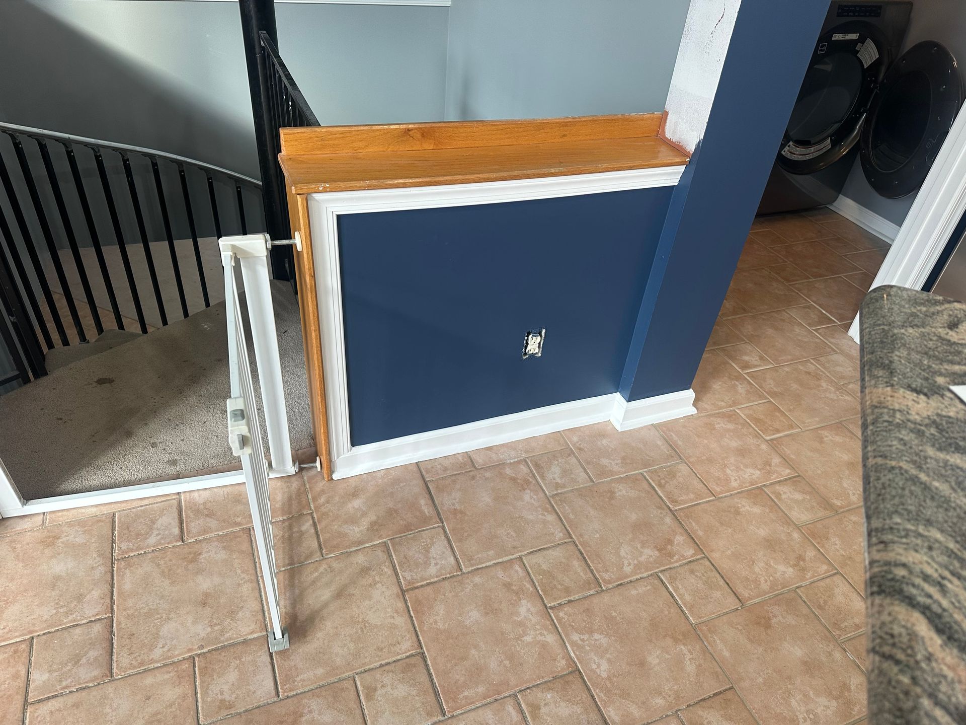 Blue stairwell wall beside a tiled floor and white railing near a carpeted area