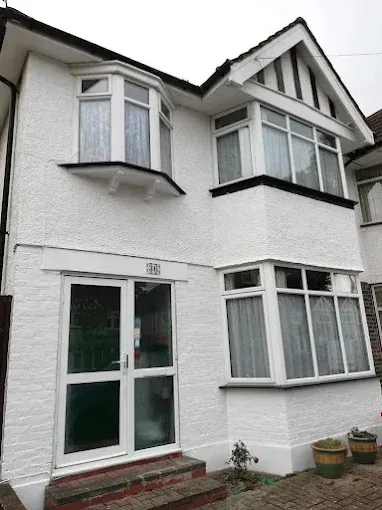 White two-story house exterior with bay windows and a green front door