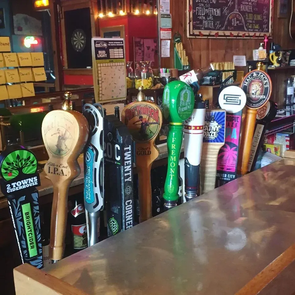 Row of colorful beer taps at a wooden bar in a dimly lit pub