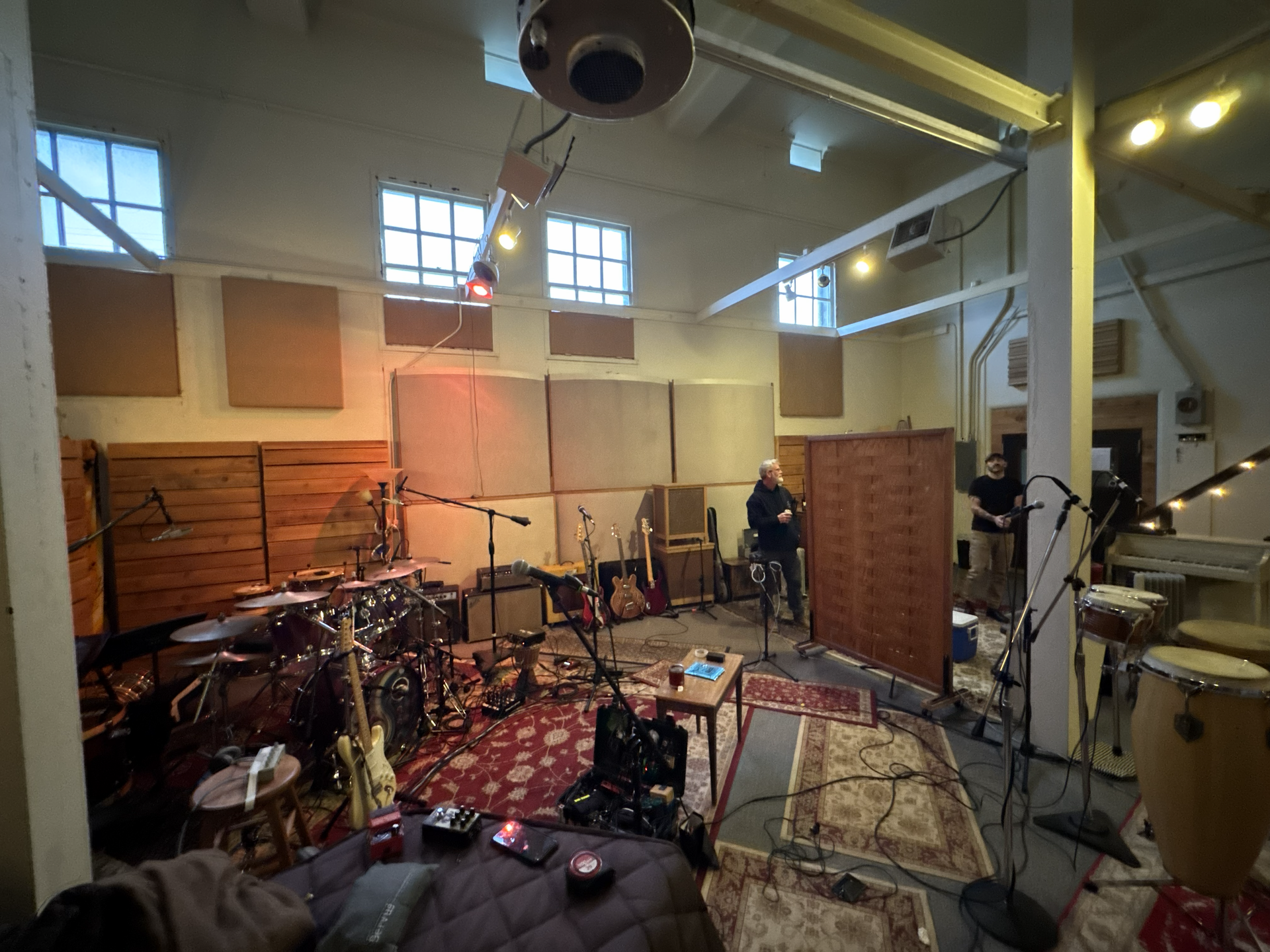 Recording studio with drum set, microphones, rugs, and soundproofing panels