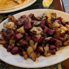 Plate of roasted meat and potatoes on a table, with a lemon wedge in the background