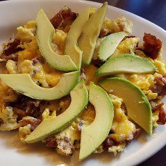 Plate of nachos topped with melted cheese and sliced avocado