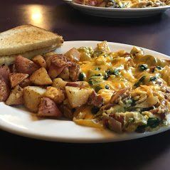 Breakfast plate with potatoes, cheesy eggs, and toast on a restaurant table