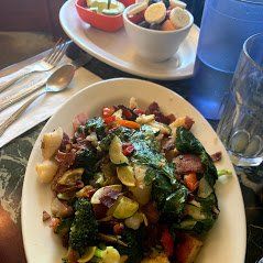 Plate of mixed vegetable salad with broccoli, potatoes, and tomatoes on a restaurant table