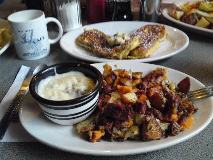 Breakfast plate with scrambled eggs, potatoes, toast, and a cup of coffee on a table