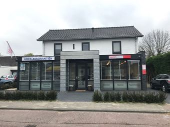 Een wit gebouw met een bordje met de tekst 'hoge assurance' erop
