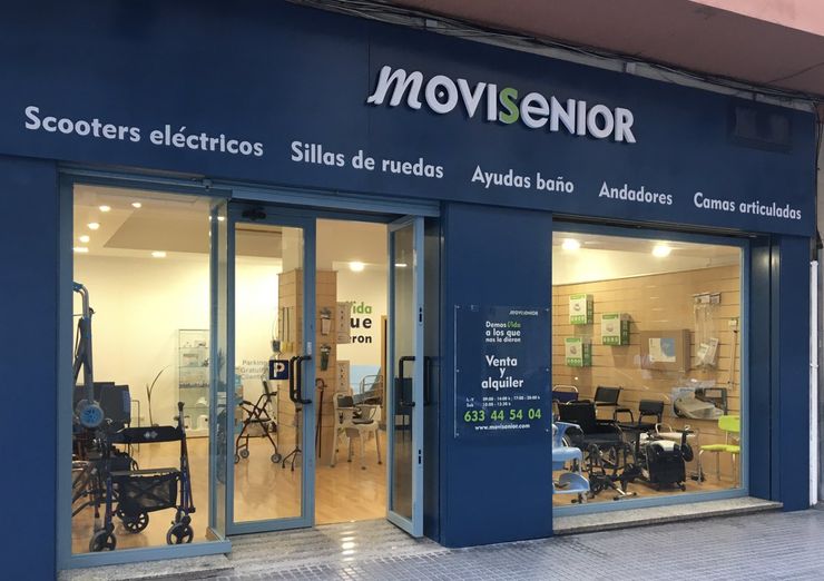 Escaparate de Movisénior con scooters, sillas de ruedas y productos de asistencia expuestos en un escaparate iluminado.