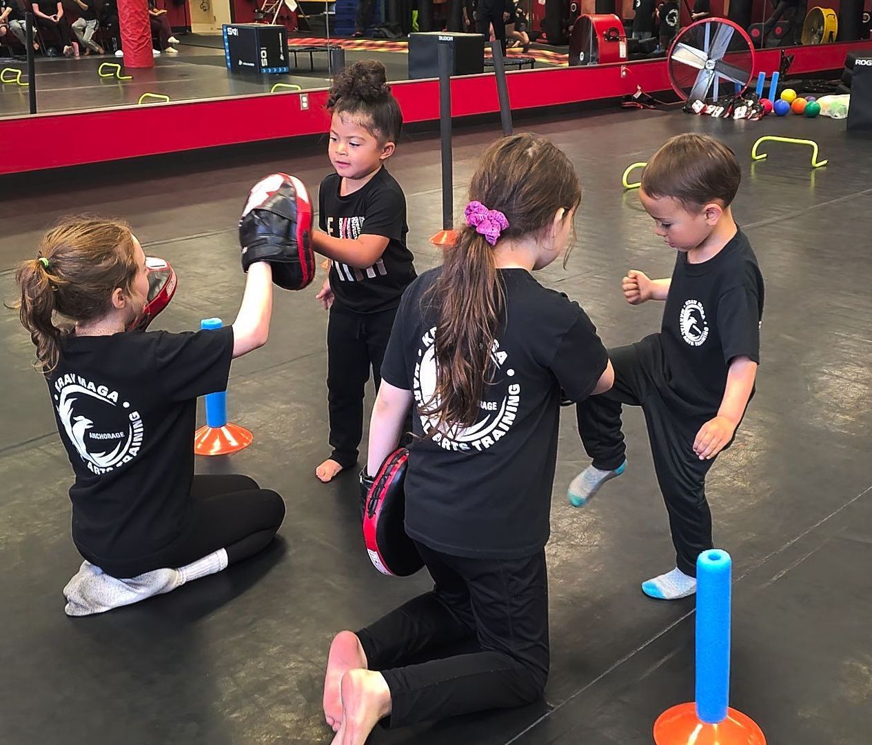 A group of young children are practicing martial arts in a gym.