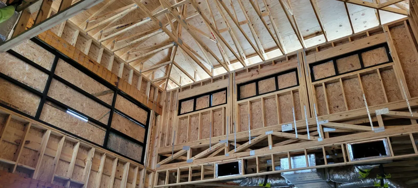 Interior of a wooden building under construction, featuring exposed framing and window openings.