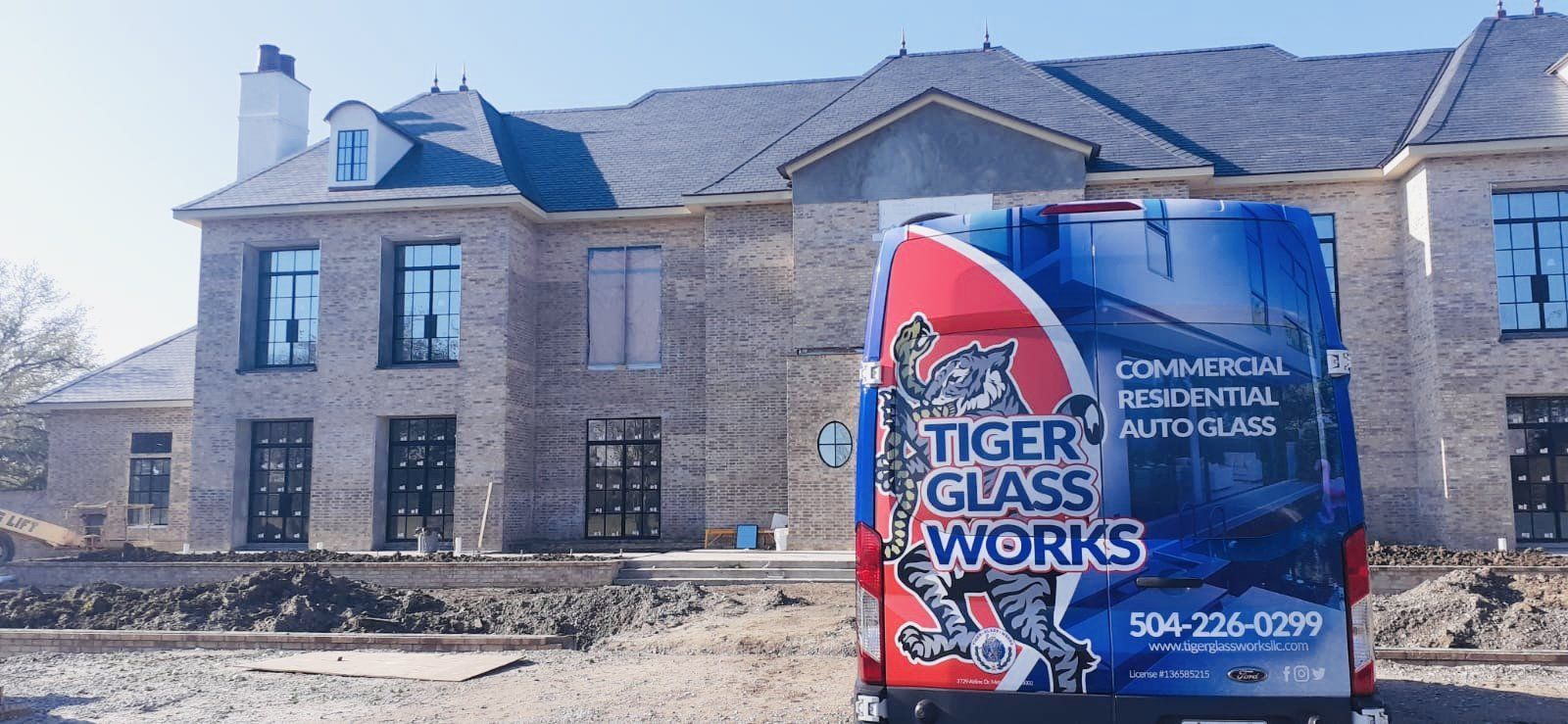 A Tiger Glass Works van parked in front of a brick house under construction.