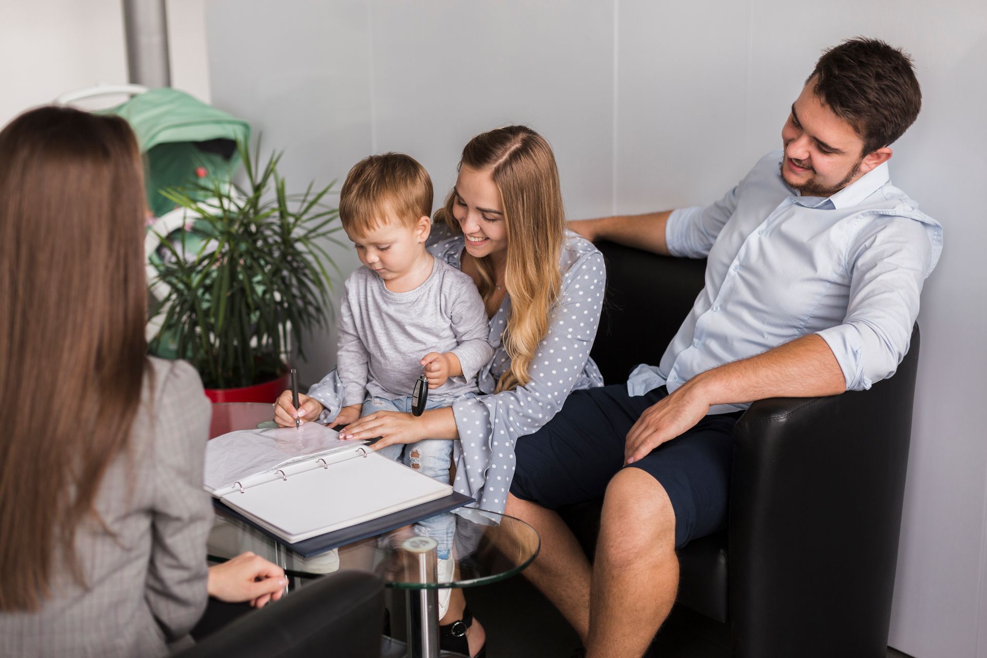 A family is sitting at a table with a woman and a child.