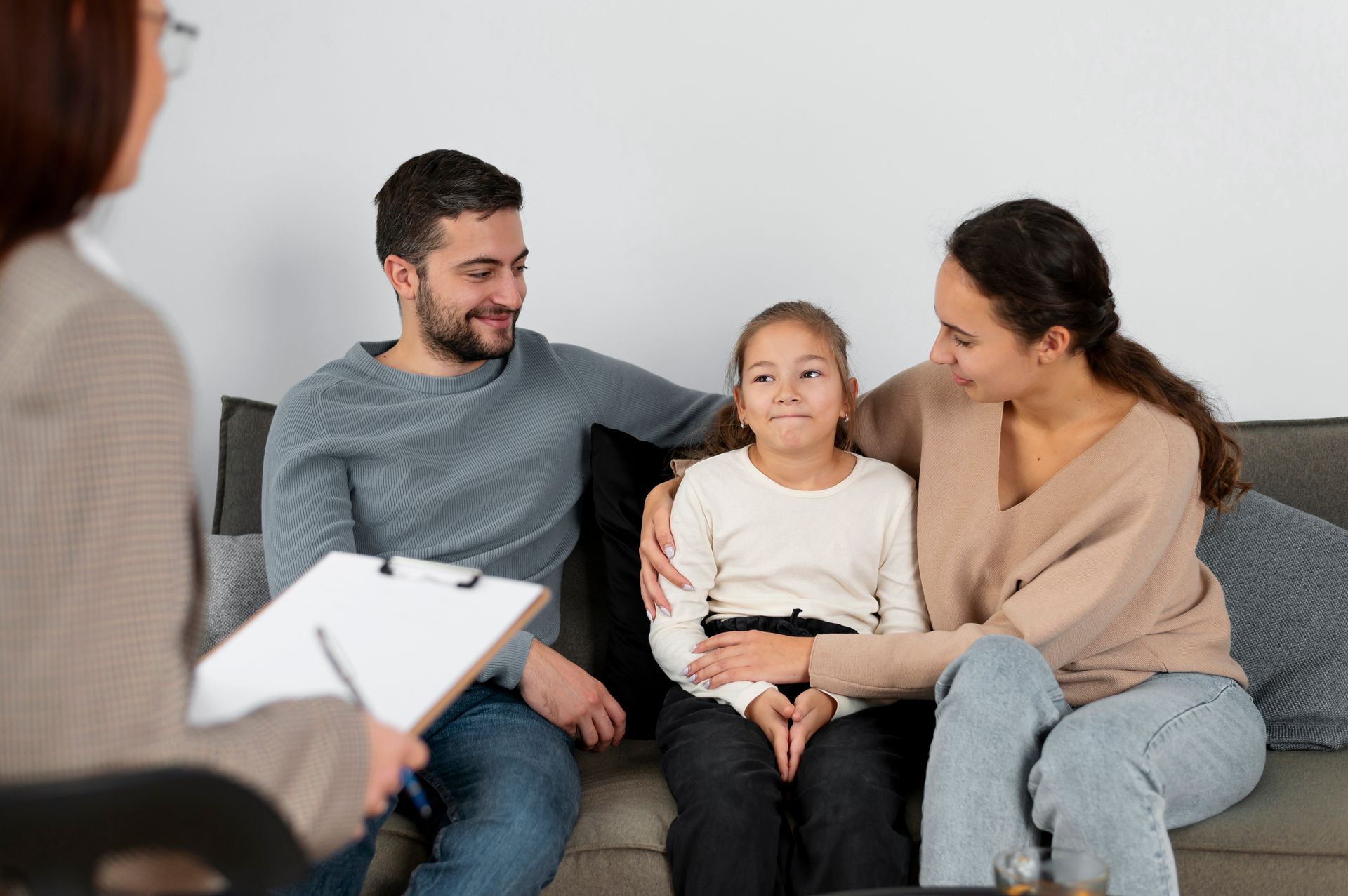 A family is sitting on a couch talking to a counselor about child custody