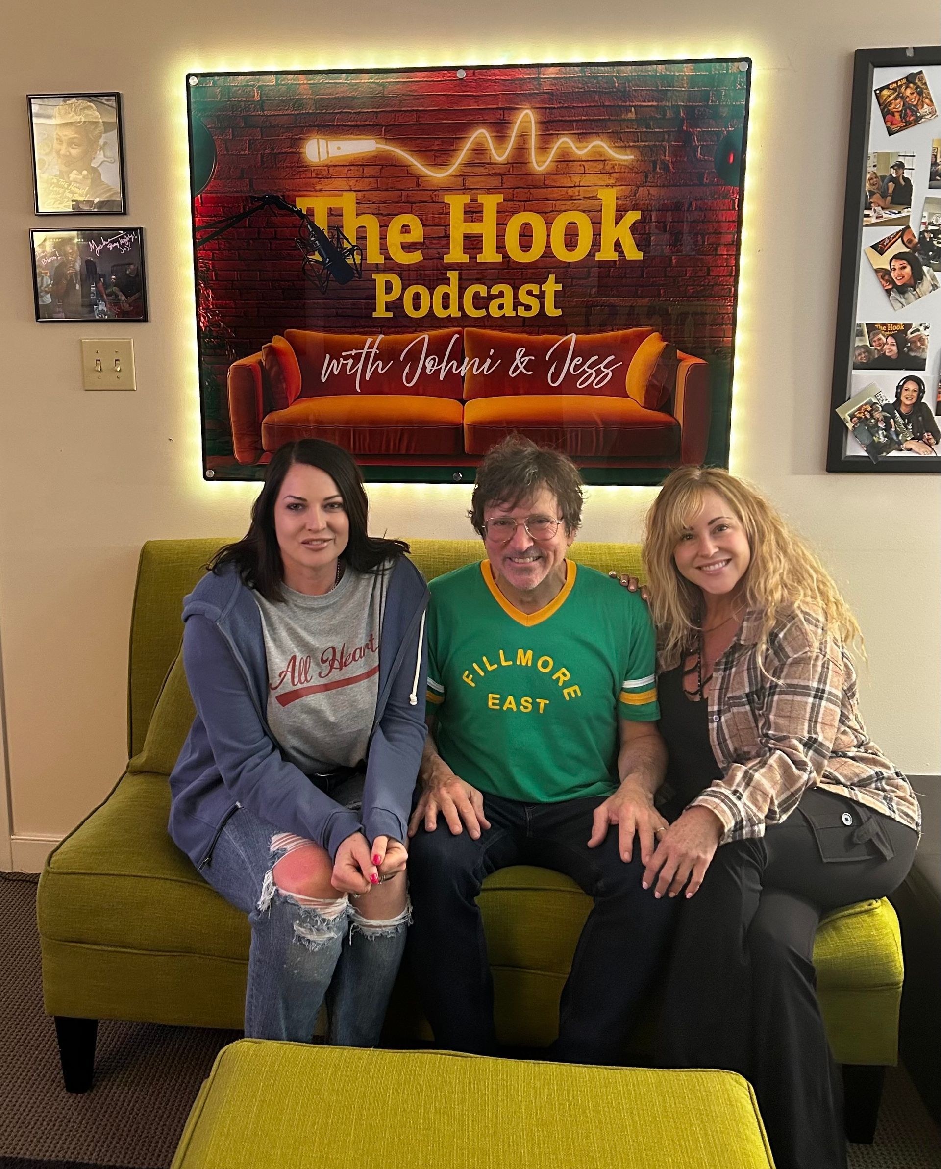 Three people seated on a couch beneath a “The Hook Podcast” sign, smiling in a studio.