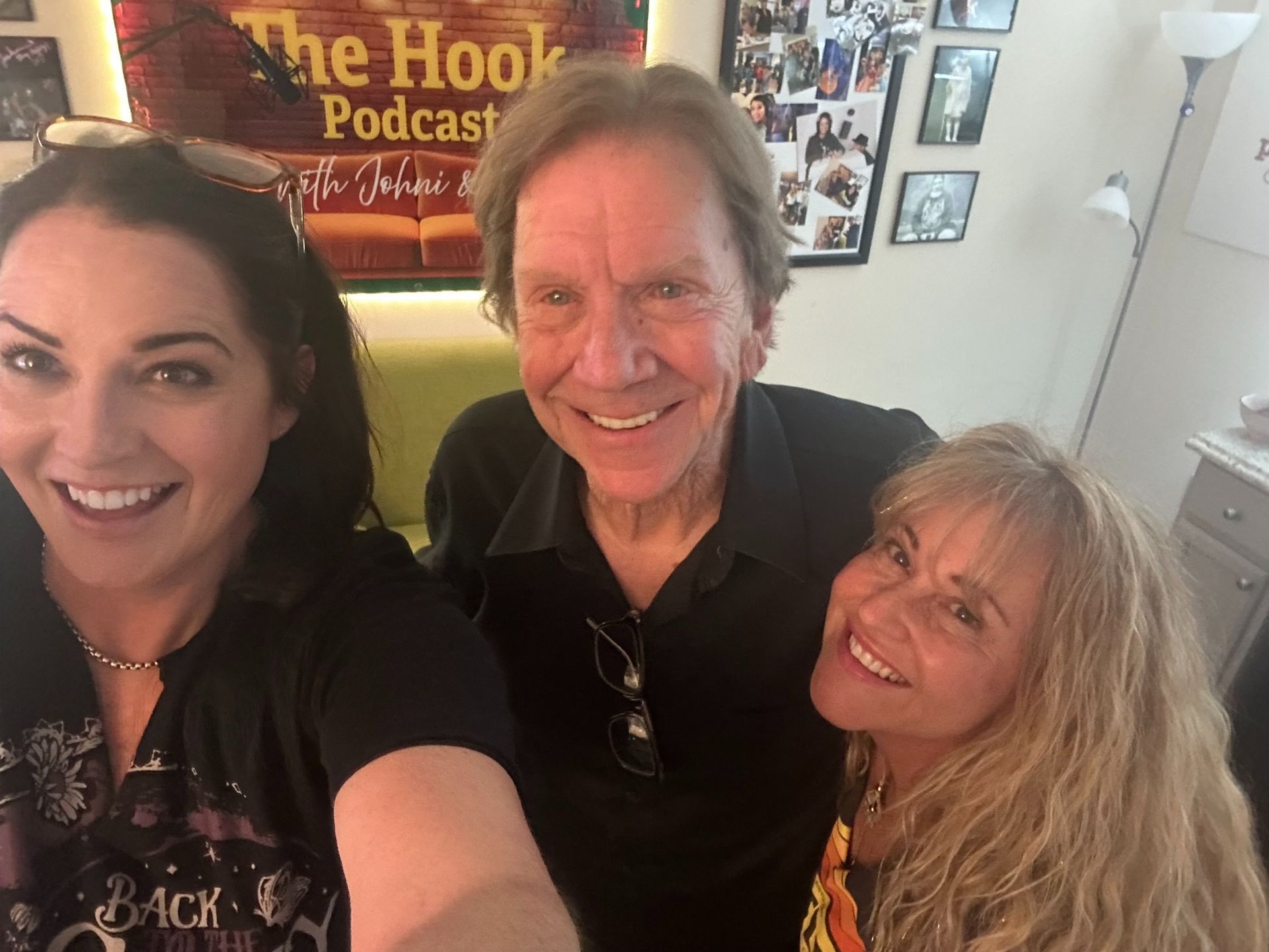 Three smiling people posing for a selfie in a podcast studio with a “The Hook Podcast” sign behind them