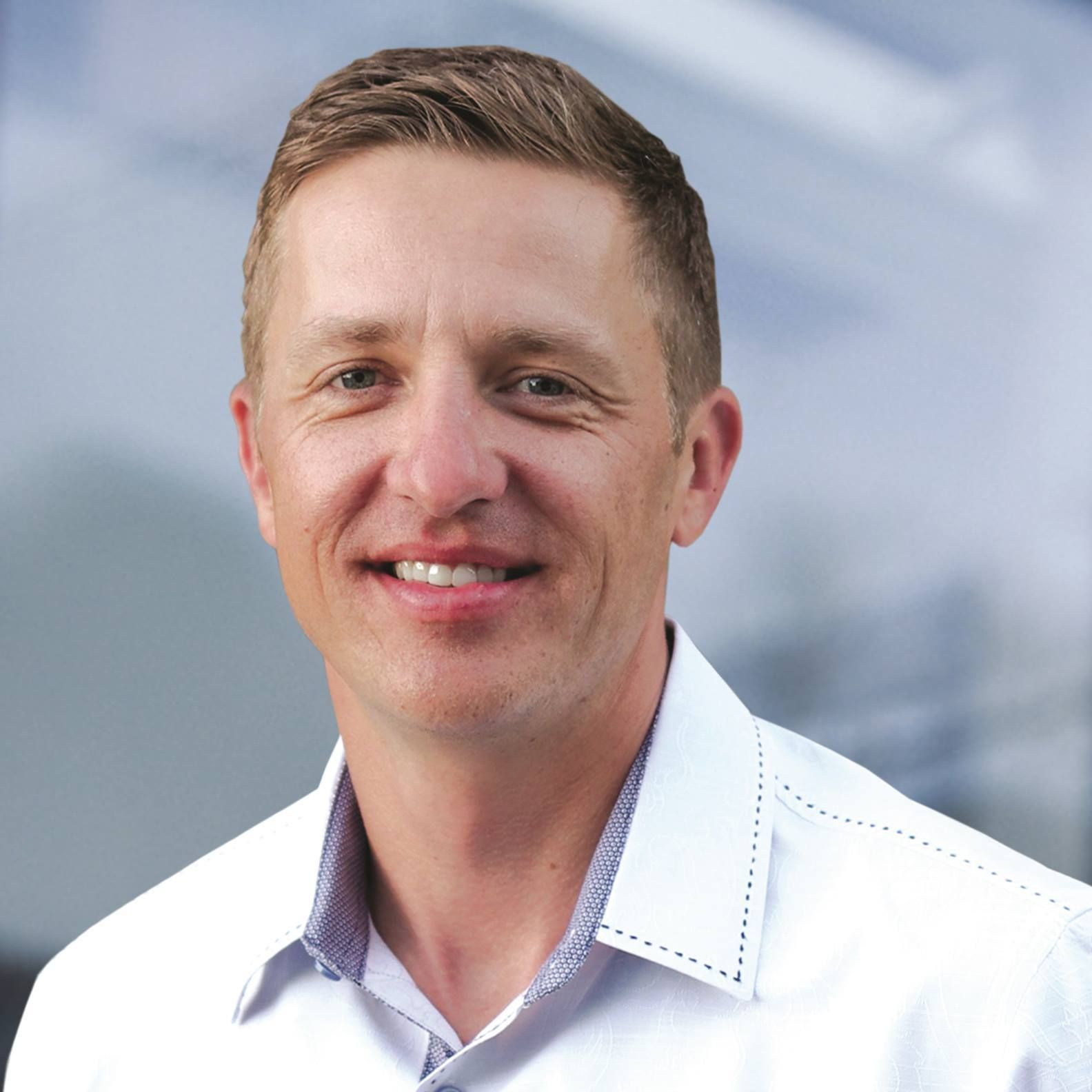 A man in a white shirt is smiling for the camera