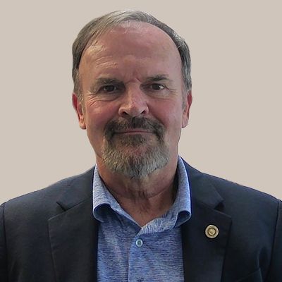 A man with a beard is wearing a suit and a blue shirt.