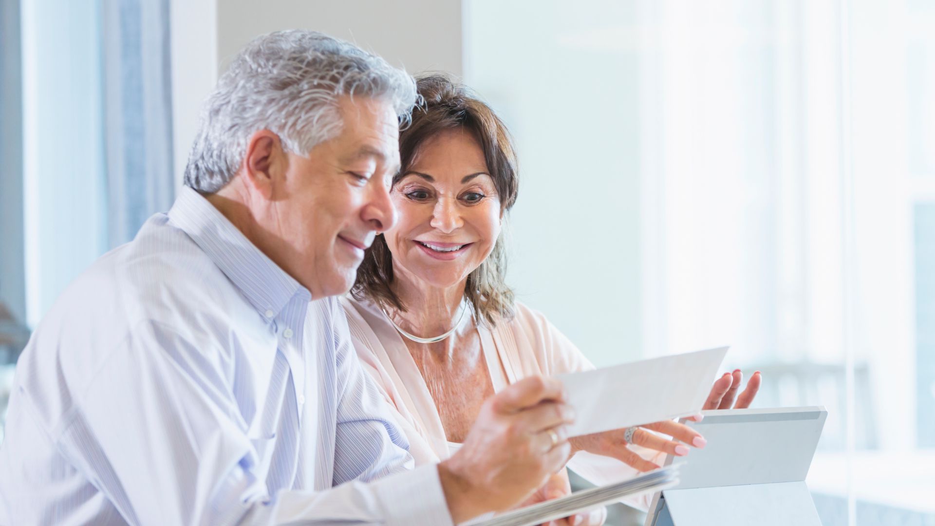 A man and a woman are looking at a tablet together.