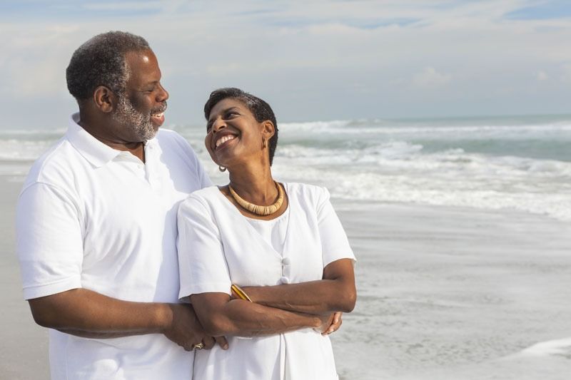 A man and a woman are standing next to each other on the beach.