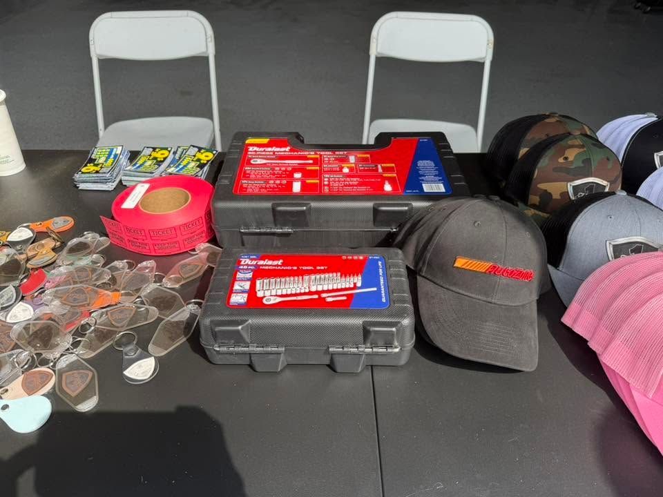 Assorted coins, hats, and packaged items displayed on a table with two white chairs behind it.