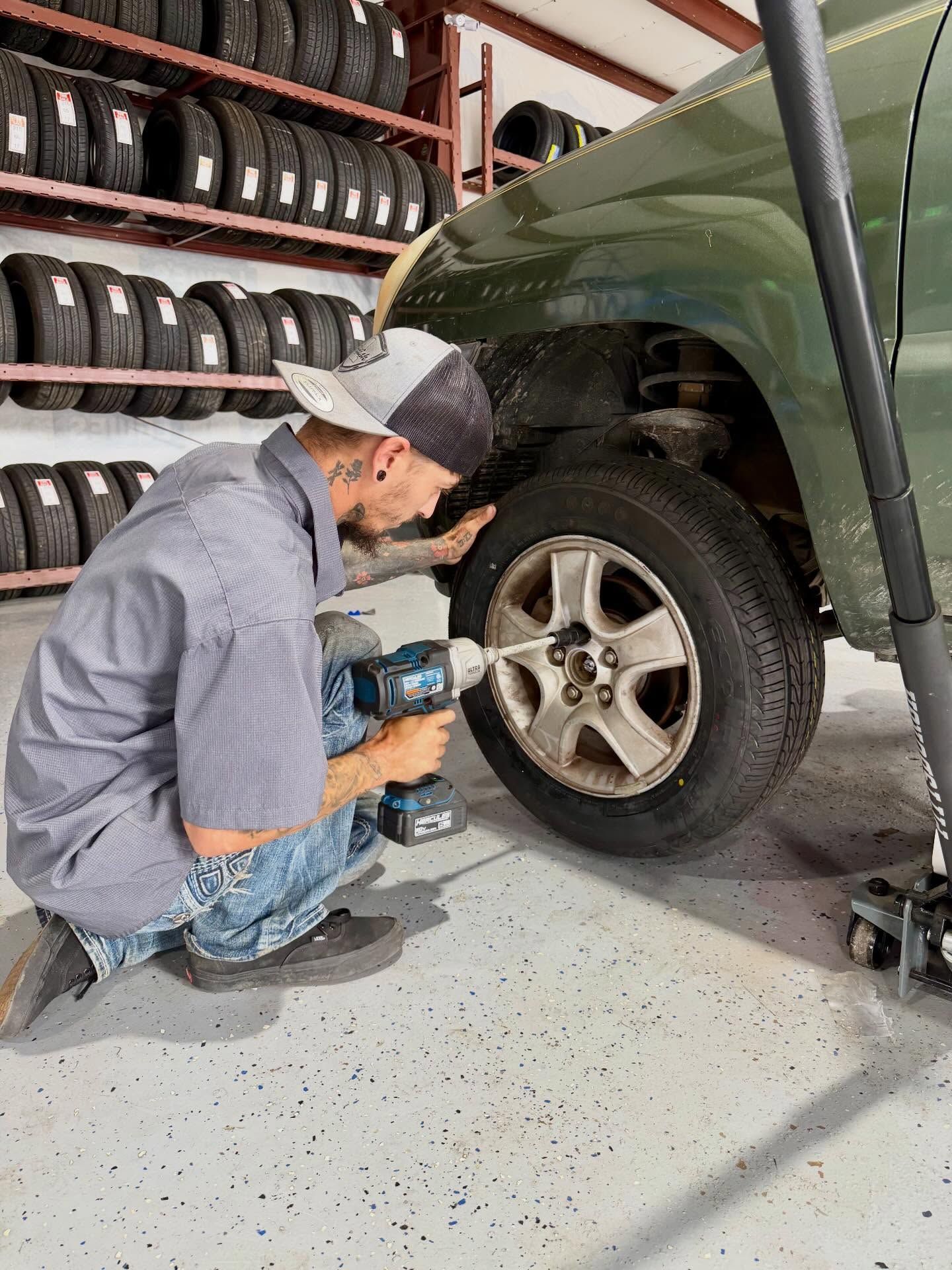 Mechanic tightening a car wheel with a power drill in a tire shop