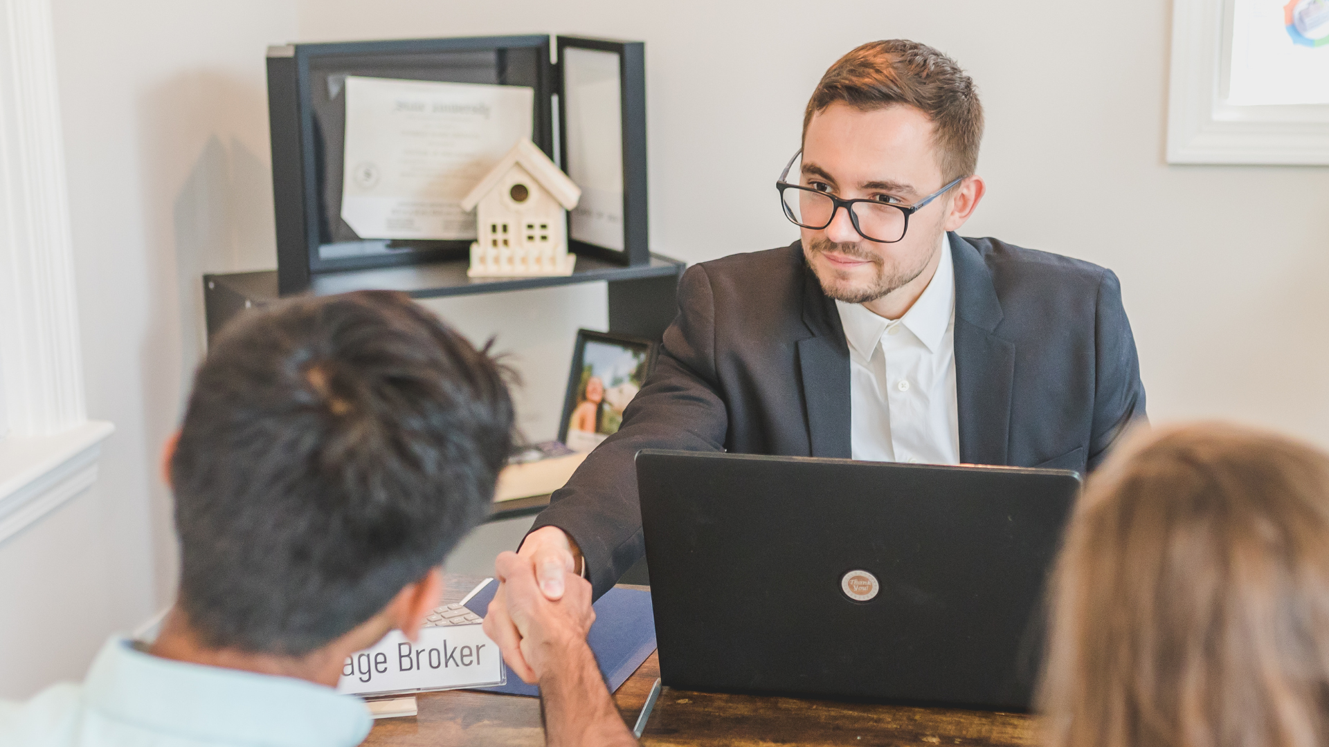 A group of business people are standing around a table holding papers.