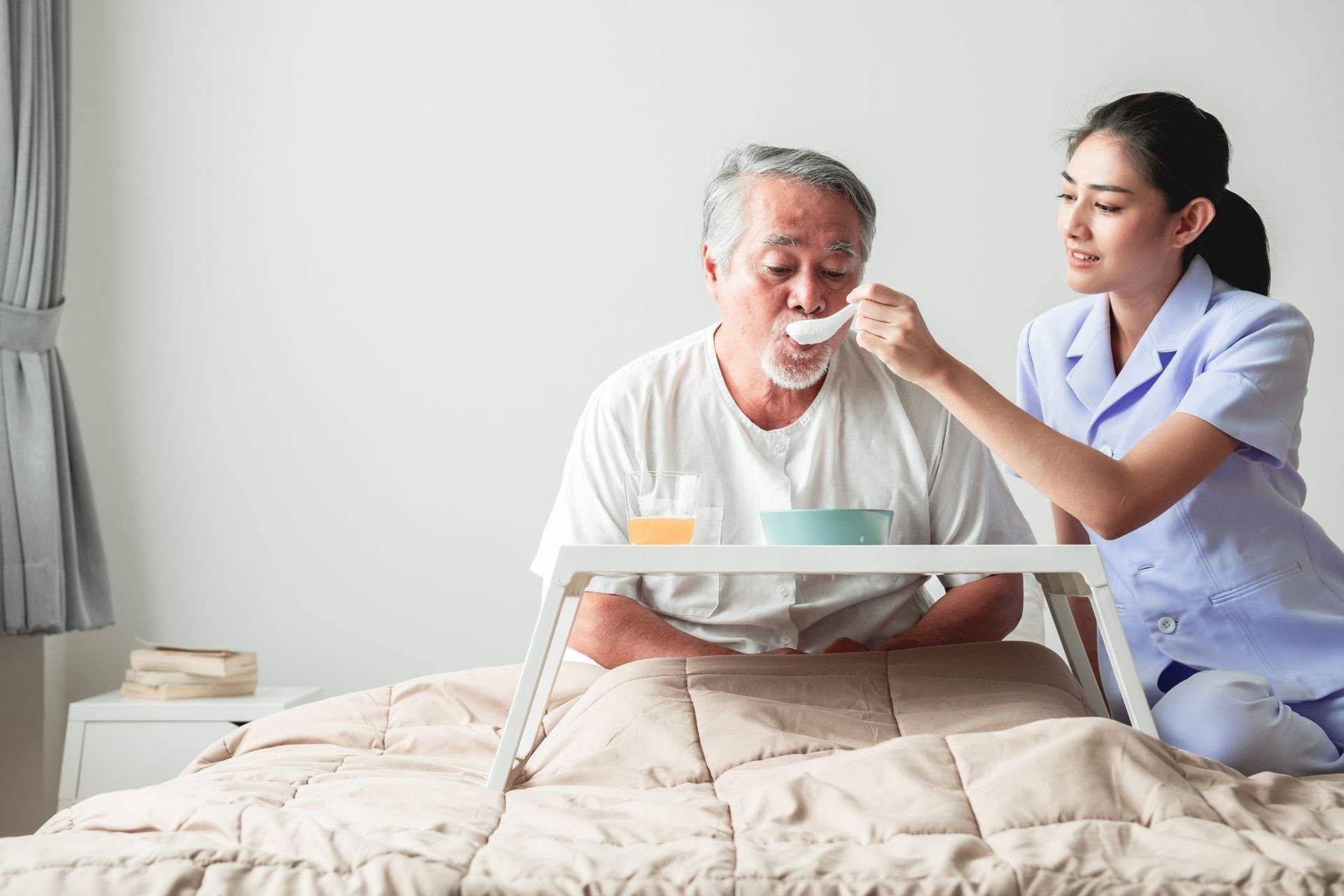 caregiver feeding food to an old person