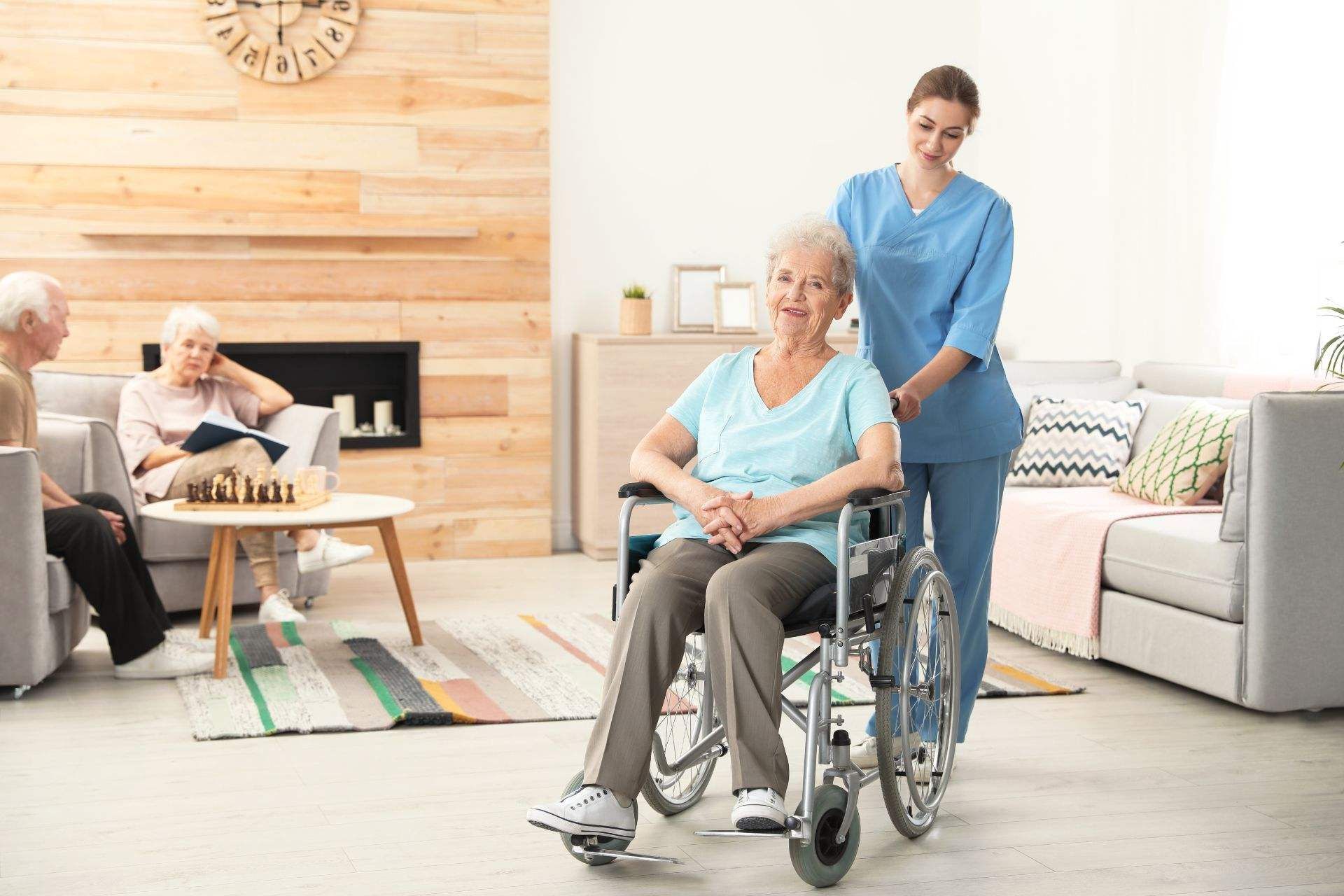 a smiling old person sits in a wheelchair with a caretaker