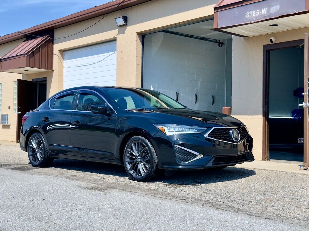 Black sedan parked outside a garage under a beige building in daylight