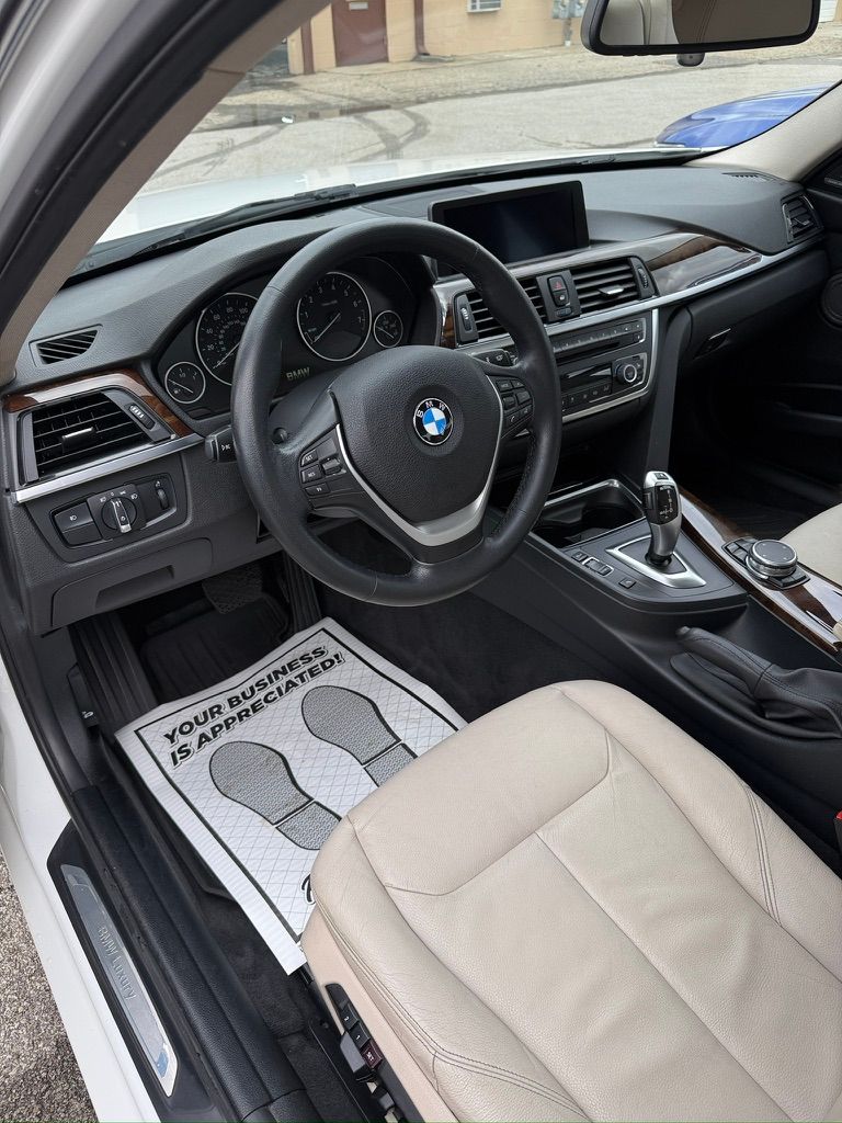 BMW car interior with beige seats, steering wheel, dashboard, and center console visible from the open driver door