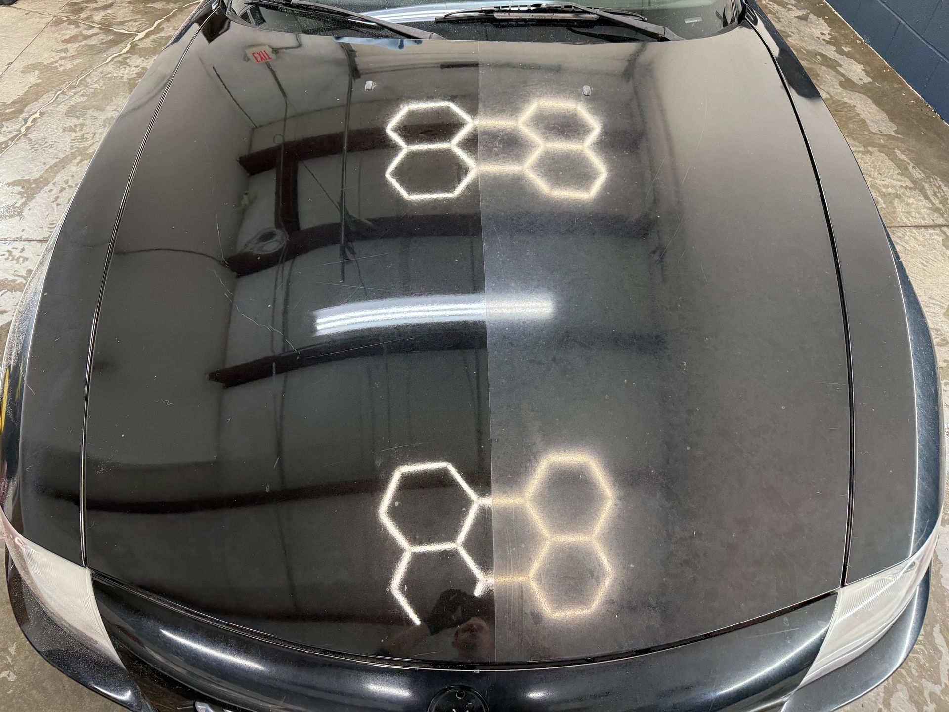 A car hood showing a 50/50 comparison: the left side is polished and reflective, while the right side is dull and hazy.