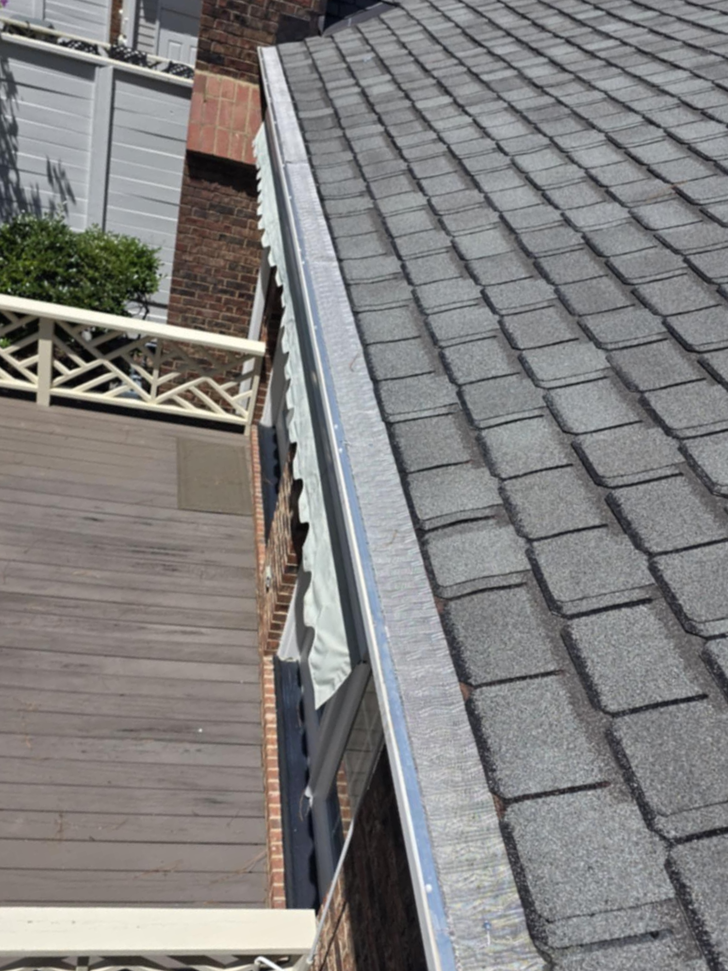 A first-person view looking down from a shingled roof, showing a foot in a dark sneaker and a tattooed leg.