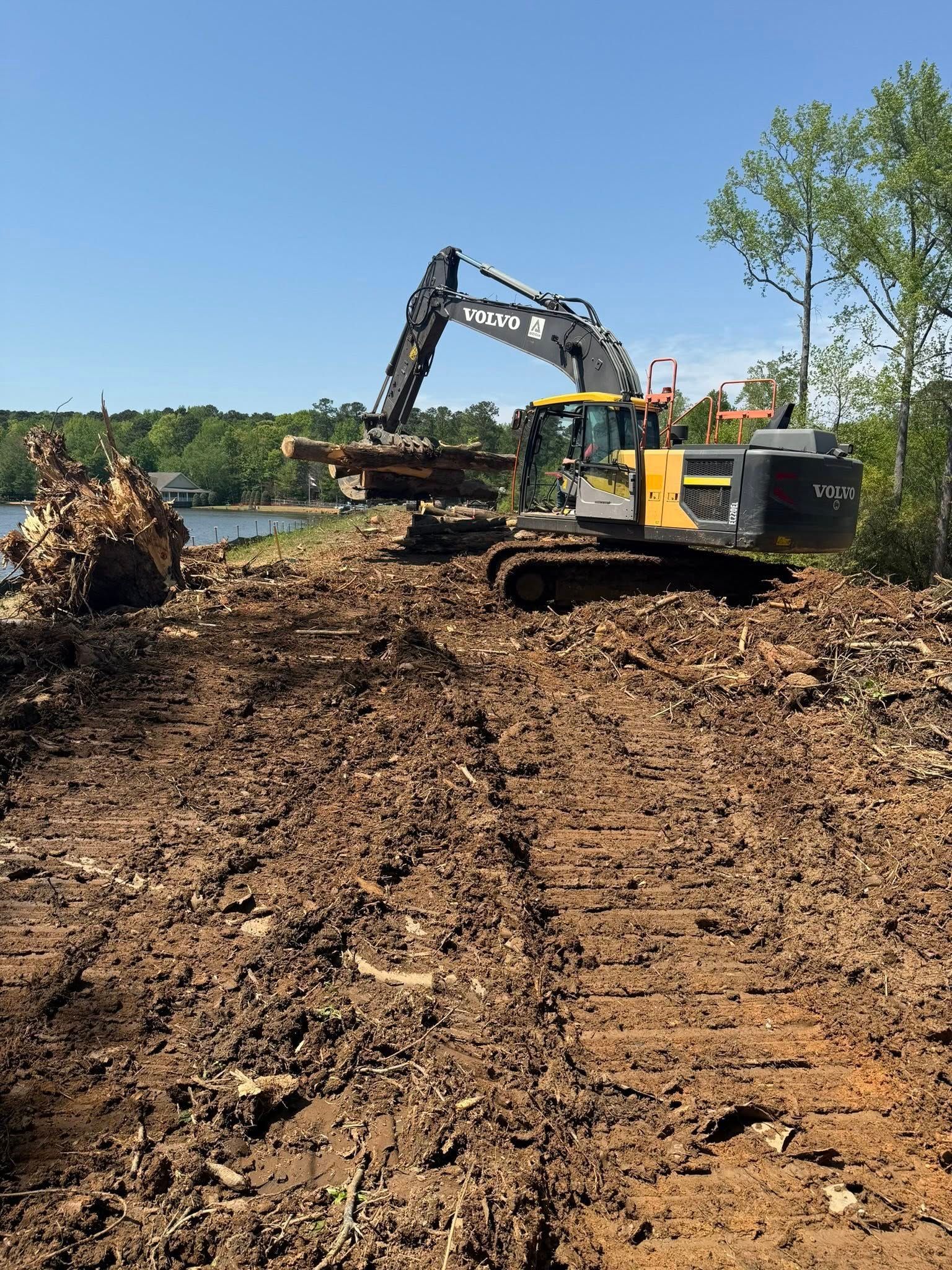 Excavator clearing dirt on a muddy construction site under a blue sky