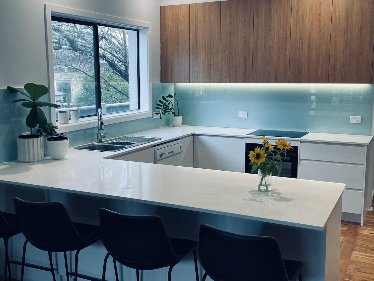 Kitchen With White Countertops, Teal Backsplash, Wood Cabinets, and Bar Seating — Gateway Manufacturing in Morisset, NSW