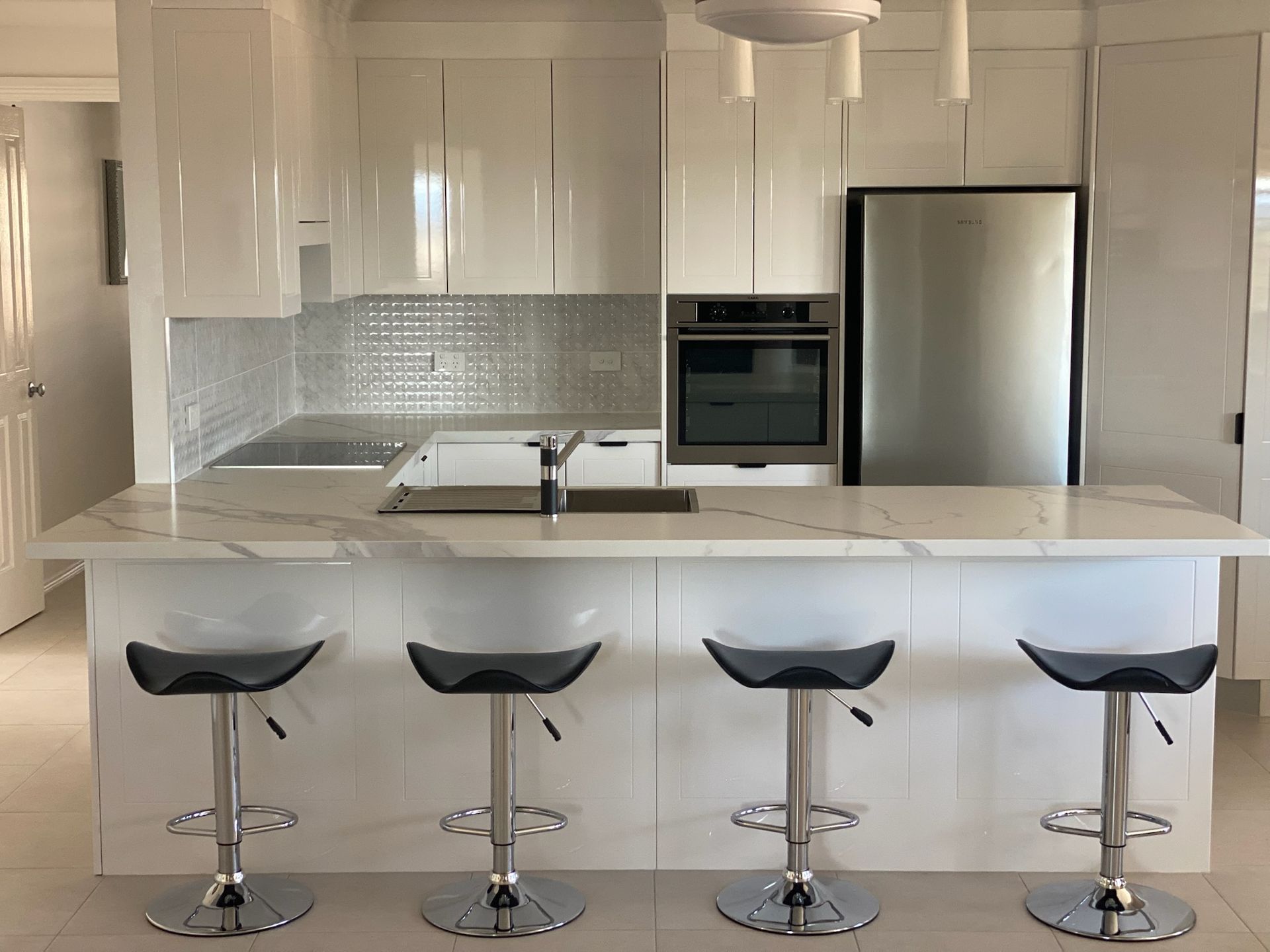 Modern White Kitchen With Island, Stainless Steel Appliances, and Bar Stools — Gateway Manufacturing in Morisset, NSW
