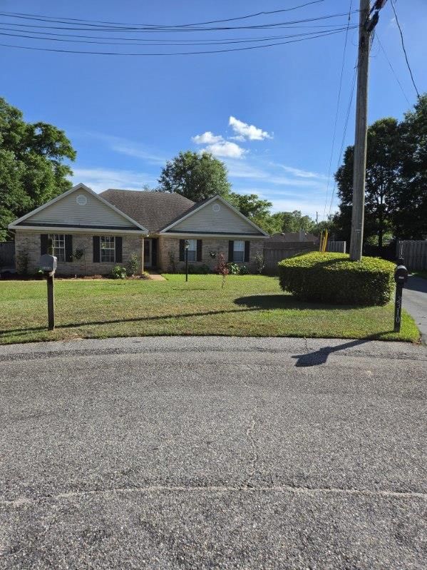 Single-story house with gray roof, front lawn, and mailbox under a bright blue sky.