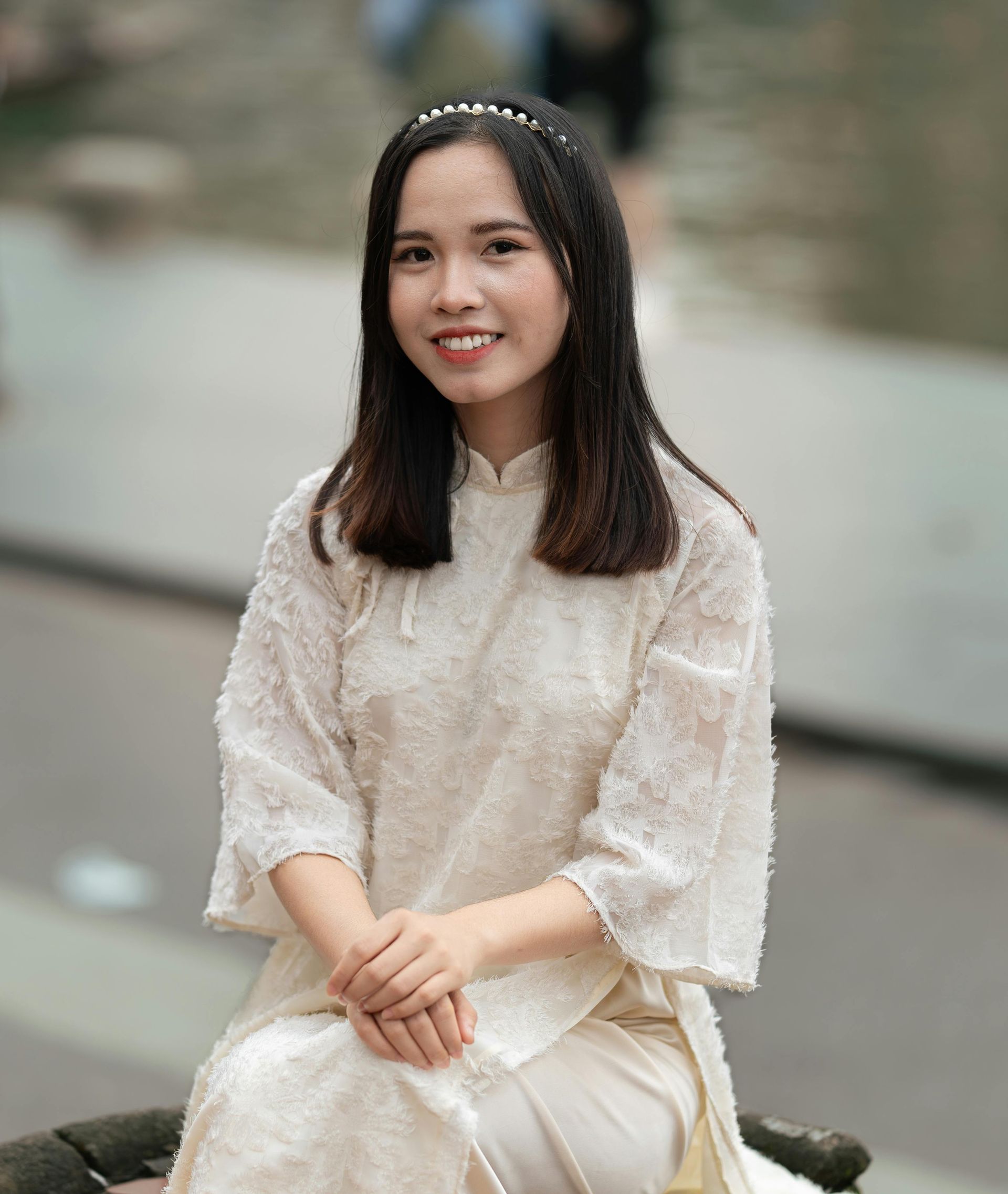 A woman in a white dress is sitting on a bench.