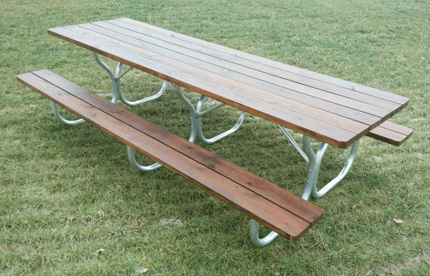 Picnic table with wooden top and bench on green grass.