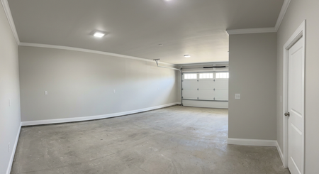 Empty garage interior with concrete floor, gray walls, and a closed white garage door.