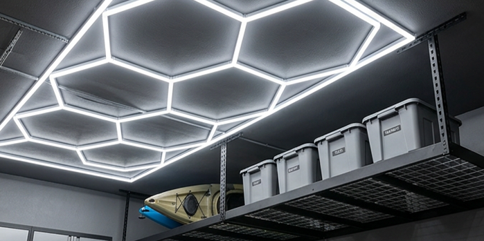 Hexagonal LED ceiling lights above metal garage shelves with gray storage bins and a kayak