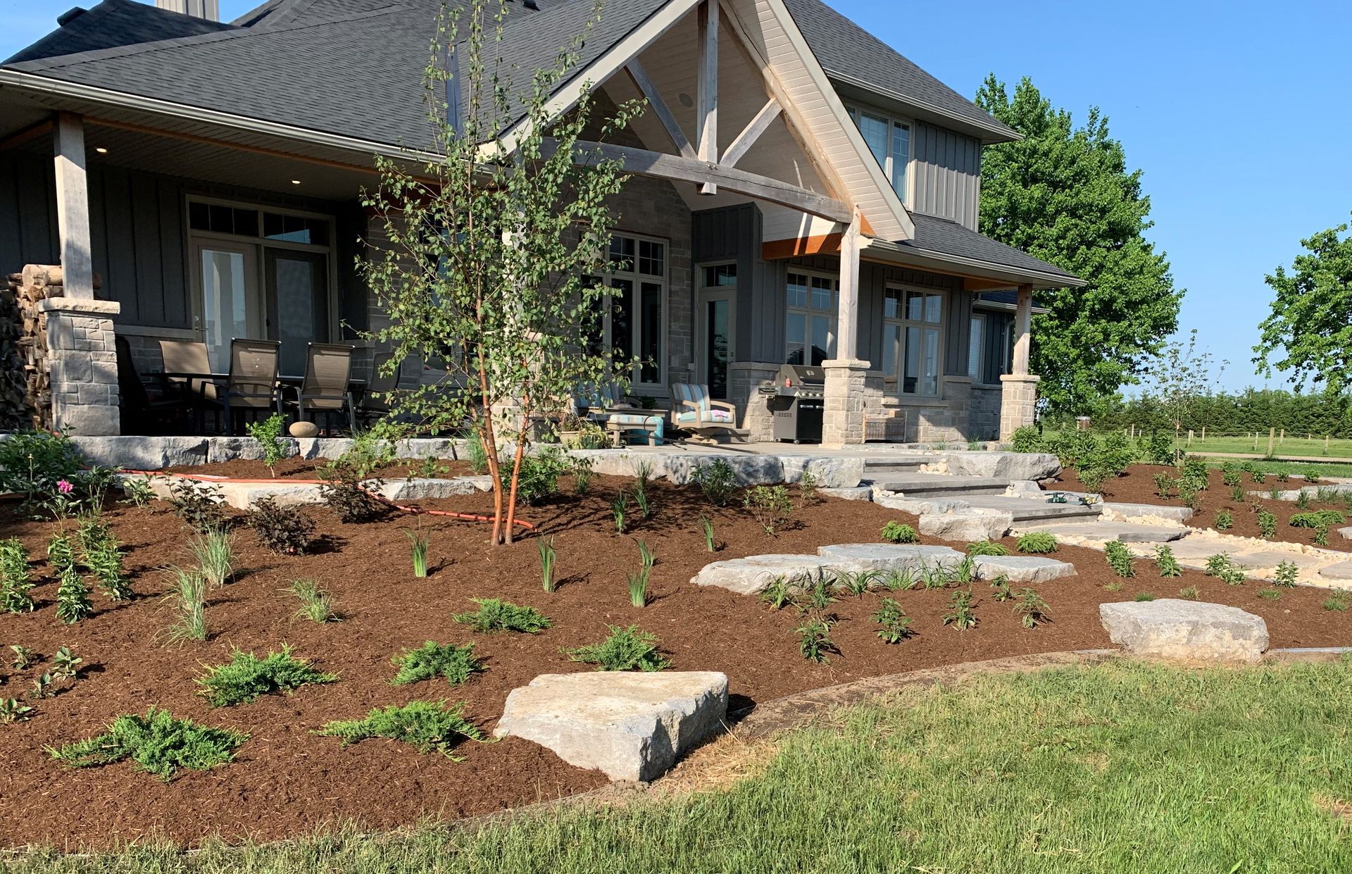 Landscaped front yard with a stone pathway leading to a two-story house with a porch and steps.