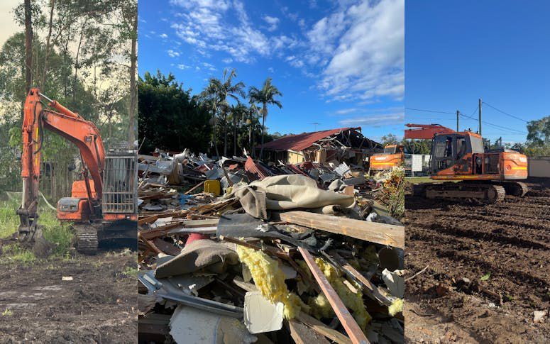 Construction site with orange excavators clearing debris and rubble under a blue sky